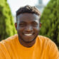 Authentic portrait of handsome smiling African American man wearing yellow casual t shirt looking at camera on the street